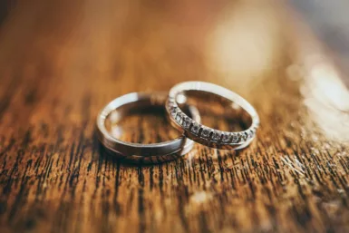 Wedding rings are displayed on a wooden surface.