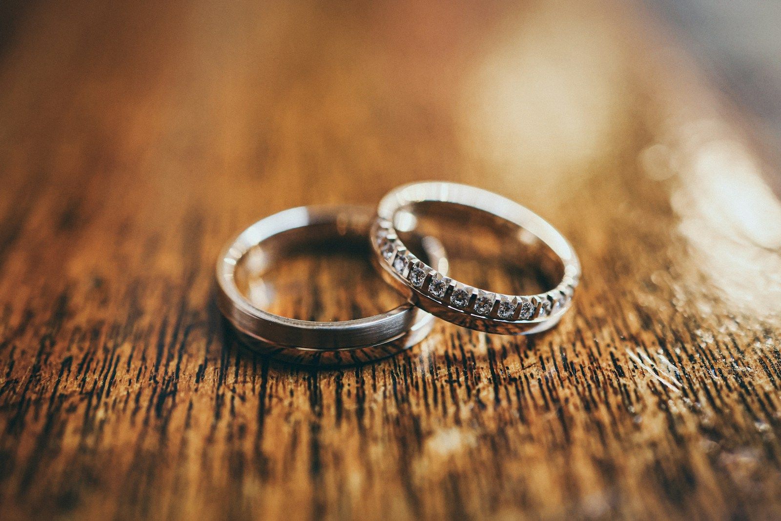 Wedding rings are displayed on a wooden surface.