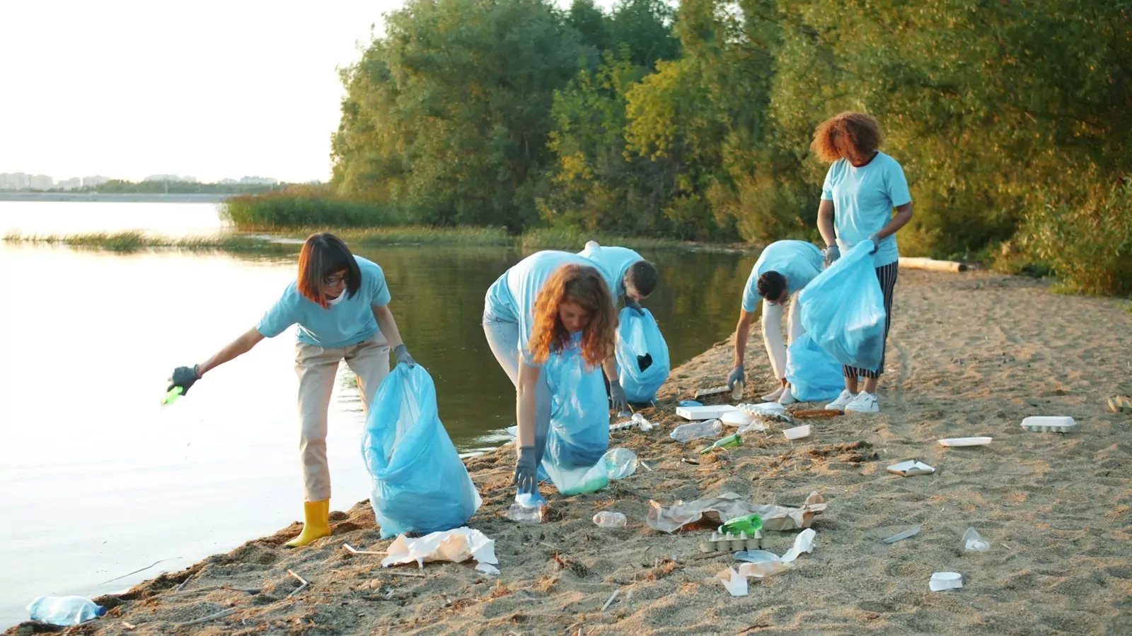 Volunteers cleaning up trash on a beach by the water